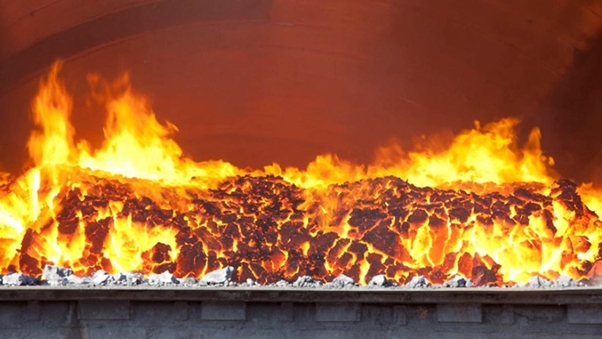 Roaring fire burns inside a massive metal oven