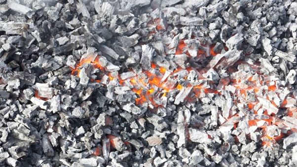 A pile of charcoal with orange flames burning